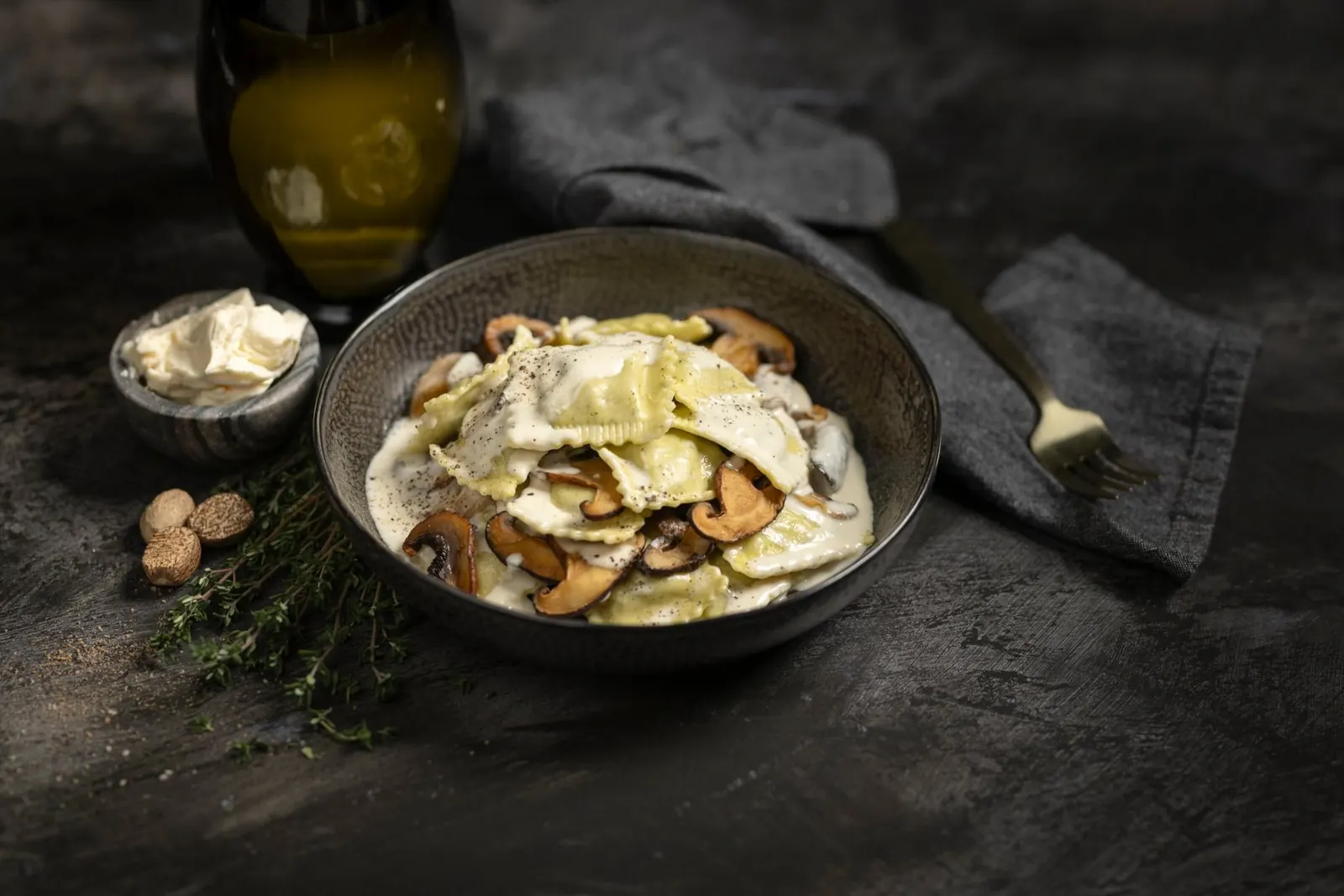 Wild mushroom mascarpone ravioli in a dark bowl with mushrooms and herbs